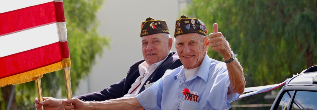 Two veterans smiling and holding an American flag during a rally.
