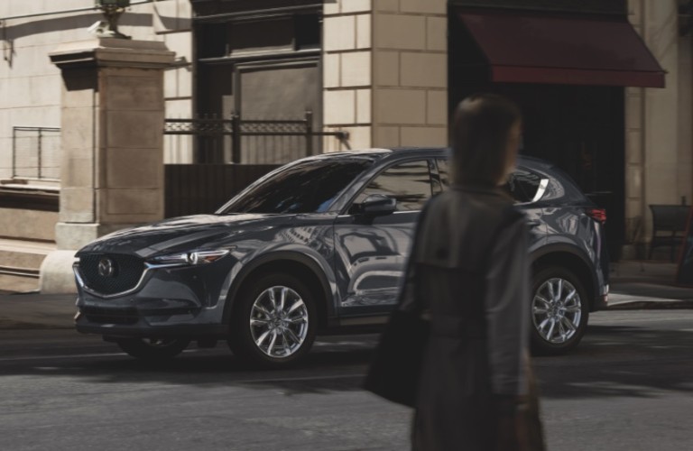 A person walking in front of a gray 2021 Mazda CX-5.