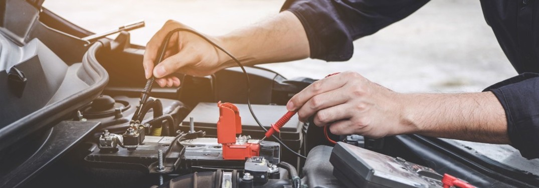 A technician testing the battery in a vehicle.