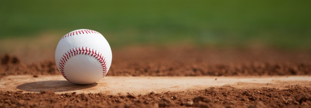 A baseball sitting on top of home plate on a baseball field.