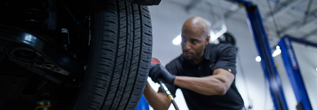 Mazda service technician using tool on tire