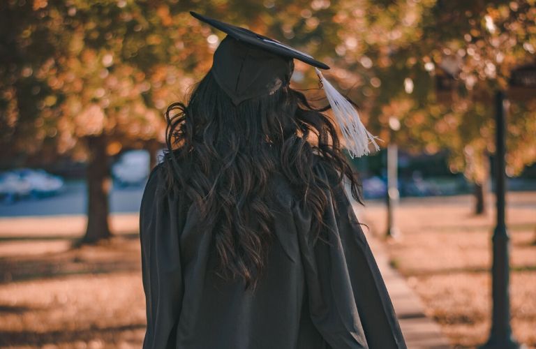 College Graduate walking across campus