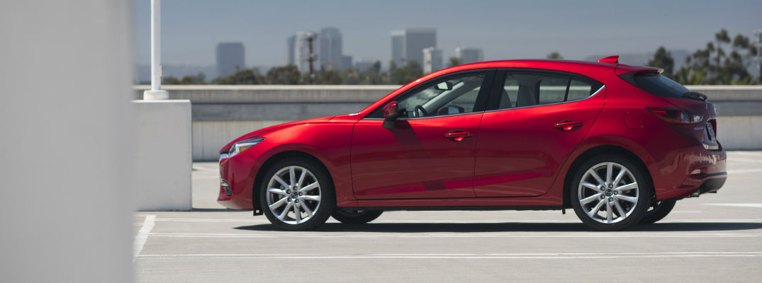 A left profile view of the 2018 Mazda3 parked on top of a parking structure.