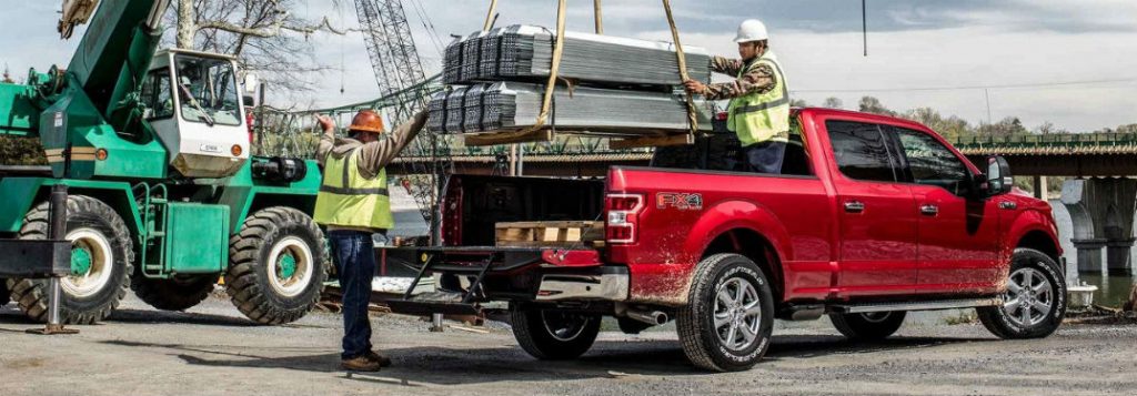 two construction workers loading the bed of a 2018 ford f-150