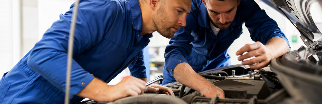 two service technicians under the hood of a vehicle