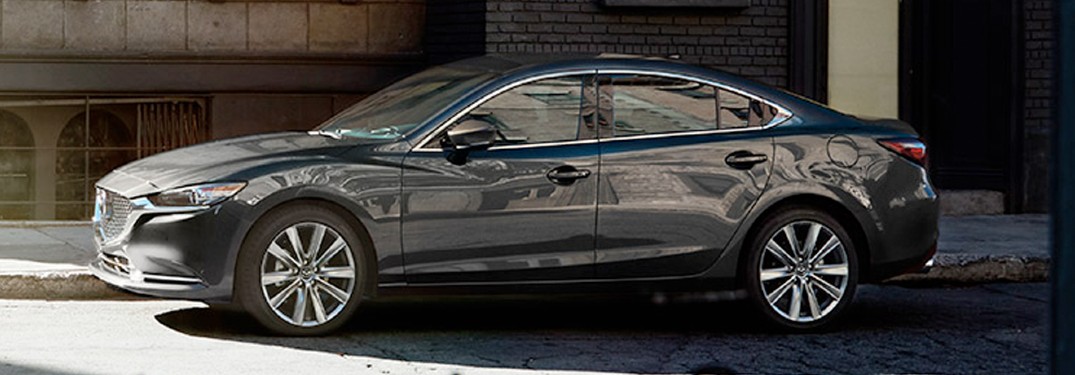 A gray 2020 Mazda6 parked in the shade next to a building.